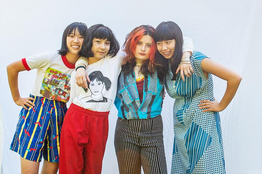 Four girls posing against a light blue backdrop