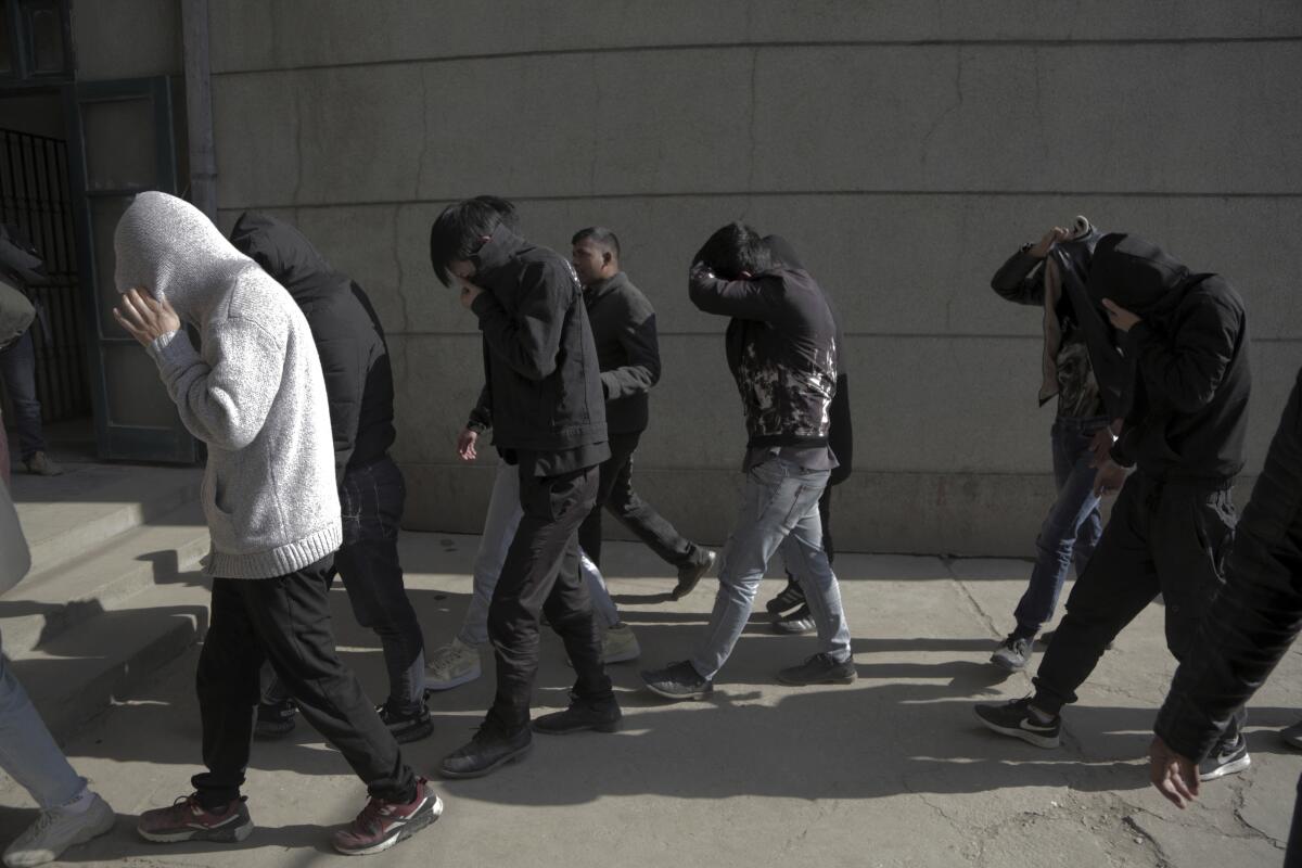 Detainees shield their faces as they are taken to a courthouse from a detention center in Kathmandu, Nepal, on Tuesday.