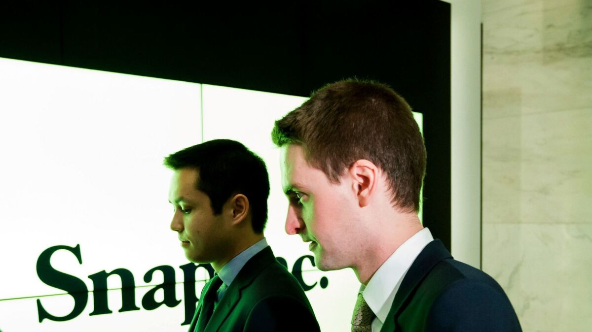 Snapchat co-founders Bobby Murphy, left, and Evan Spiegel stand together before shares of Snap Inc., the parent company of Snapchat, begin trading at the New York Stock Exchange.
