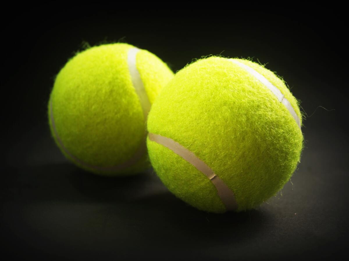 Bright yellow tennis balls with dark background.