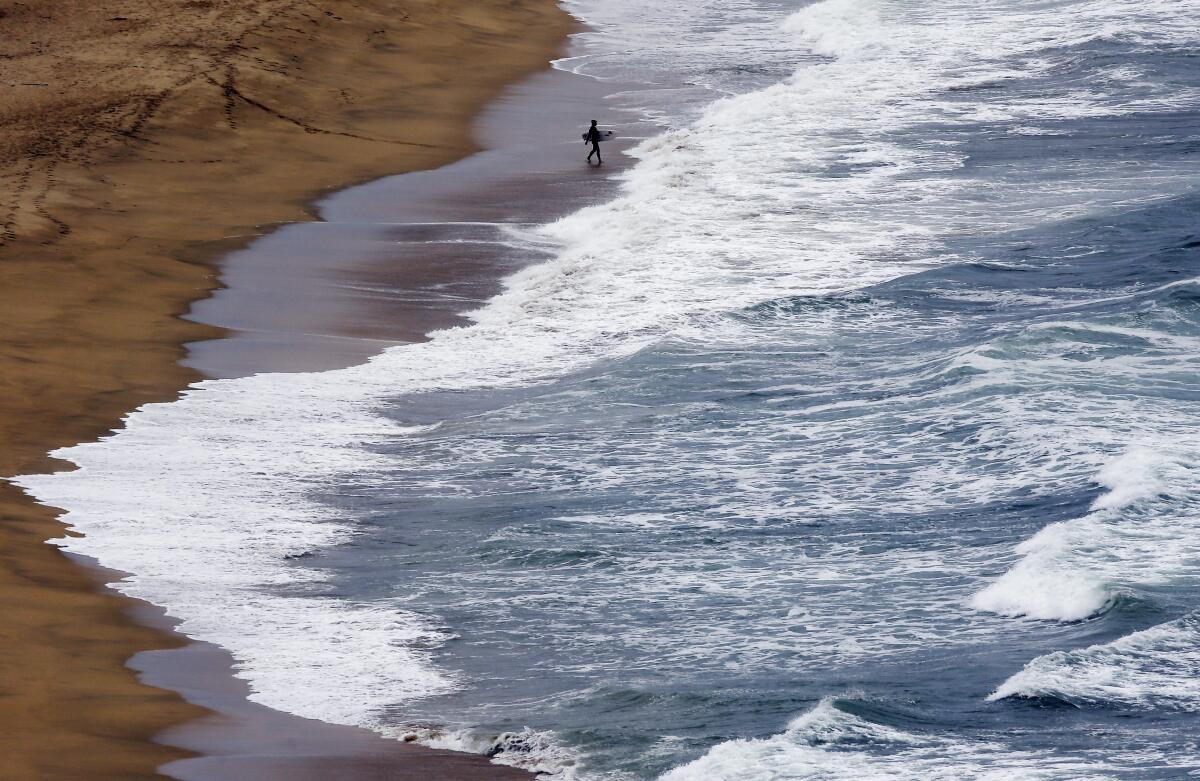 A surfer enters the water at Montara State Beach.