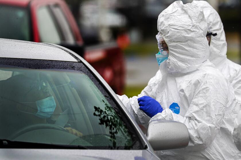 COLTON, CA - APRIL 09: Alejandra Ortiz, left, sits in her car as a nurse administers a coronavirus COVID-19 test at Arrowhead Regional Medical Center public testing drive-through in Colton, CA. (Irfan Khan / Los Angeles Times)
