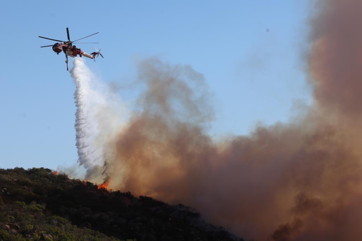 MALIBU, CALIF DECEMBER 10, 2024 - A firefighting helicopter drops water on a fire.