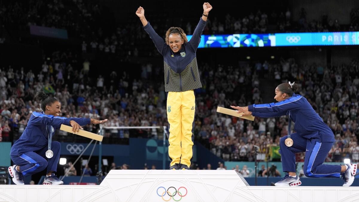 two women on a podium bowing down to the woman standing at the top