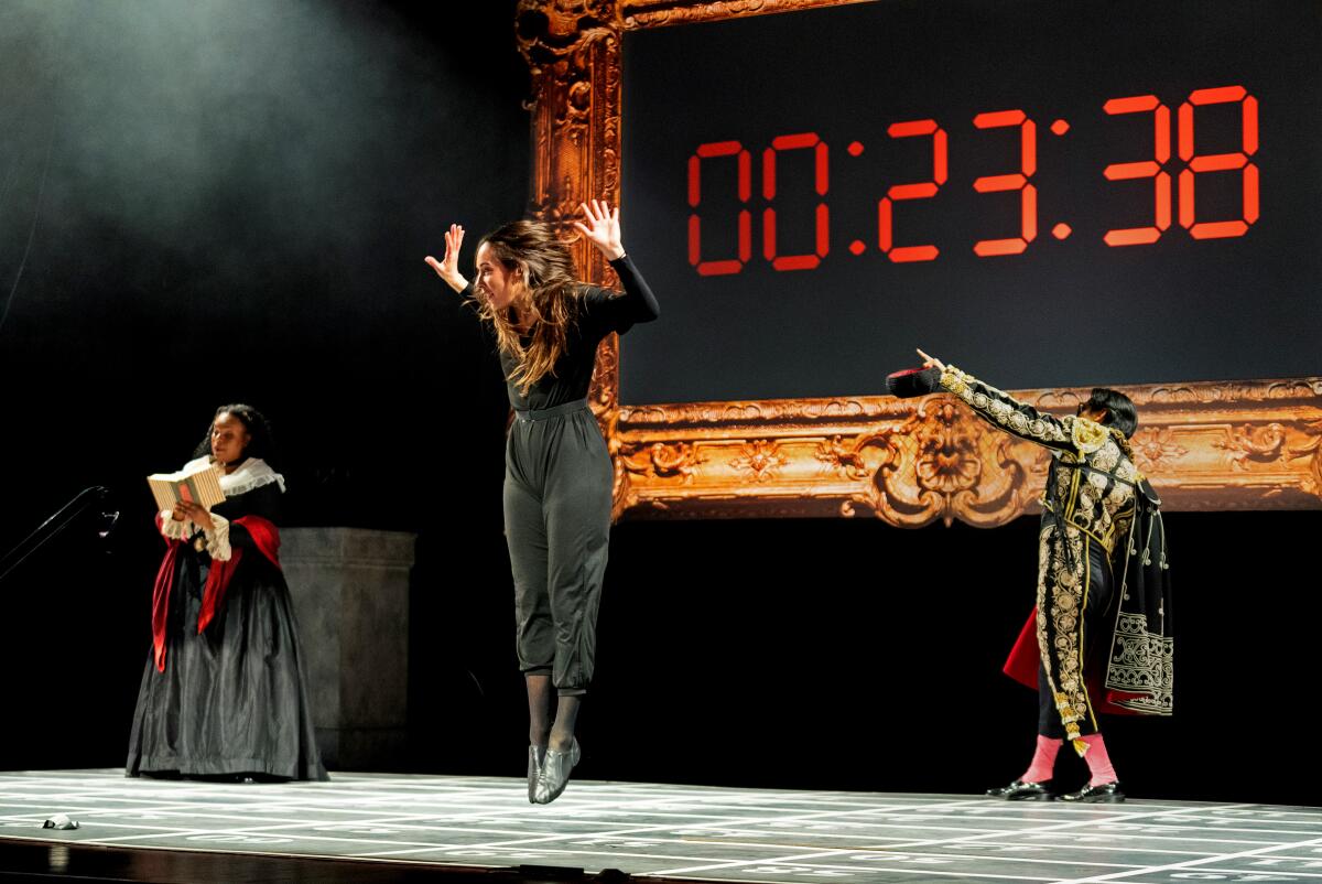 Three performers stand in front of a giant digital clock in John Cage's 'Europera 3,' presented by Detroit Opera.