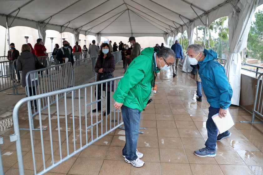 Orange County CEO Frank Kim, center, takes a question as others line up for the Pfizer COVID-19 vaccine on Saturday.
