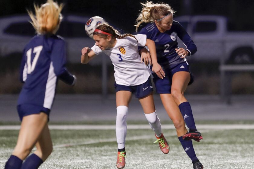 Marina's Riley Crosby (3) heads the ball as she is hit by Newport Harbor's Laine Briggs during Wave League girls' soccer game on Tuesday.