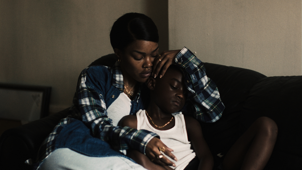 A woman hugs a young boy on a couch.