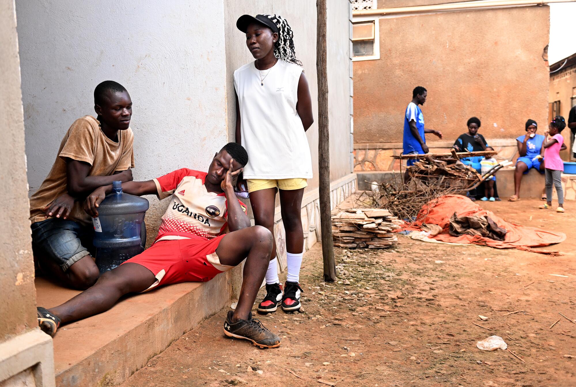 An exhausted Dennis Kasumba rests as he hangs out with friends and players after baseball practice.