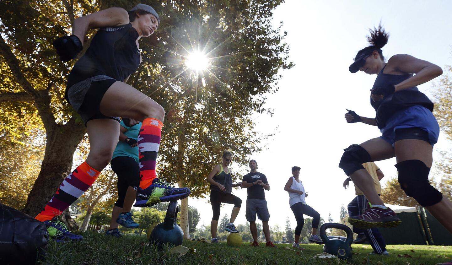 On a warm Monday, Tracy Riepl, left, and Diana Kratt do a leg and cardio exercise with others in a class called Gut Check Fitness Los Angeles at Warner Park in Woodland Hills.