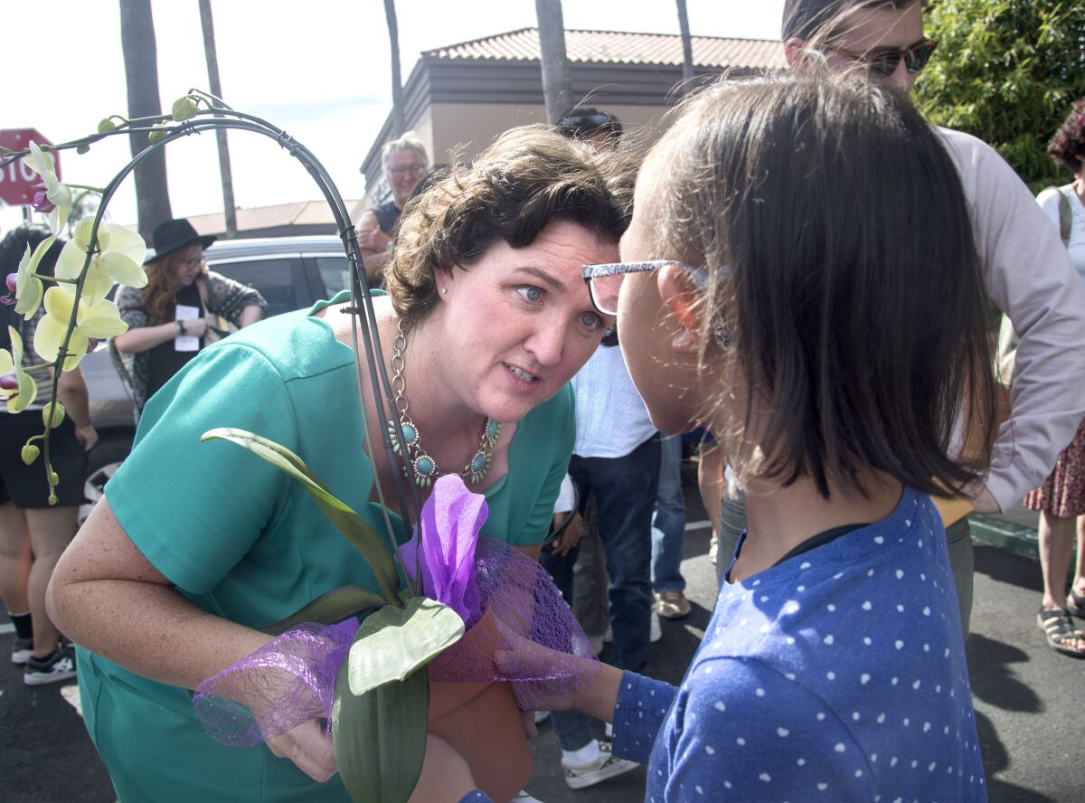 Congresswoman Katie Porter receives a flower from a child. 