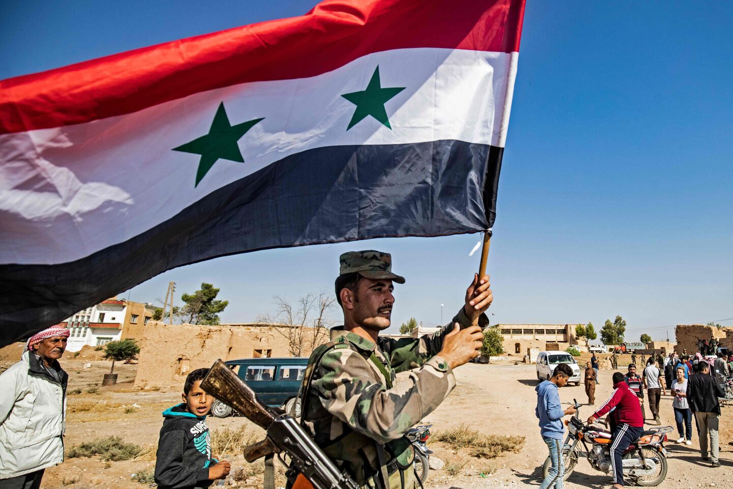 A Syrian regime soldier waves the national flag