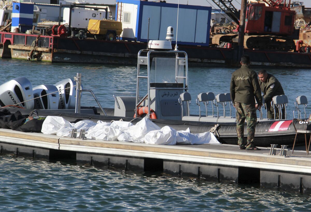 Tunisian coast guards stand beside the covered dead bodies of migrants in the port of Sfax in central Tunisia on Thursday.