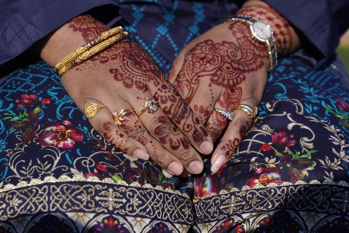 FILE - Tasneem Salam hands are decorated with henna as she attends an Eid al-Fitr celebration in Overpeck County Park in Ridgefield Park, N.J., Thursday, May 13, 2021. This year, in a rare convergence, Judaism’s Passover, Christianity’s Easter and Islam’s holy month of Ramadan are interlapping in April with holy days for Buddhists, Baha’is, Sikhs, Jains and Hindus, offering different faith groups a chance to share meals and rituals in a range of interfaith events. (AP Photo/Seth Wenig, File)