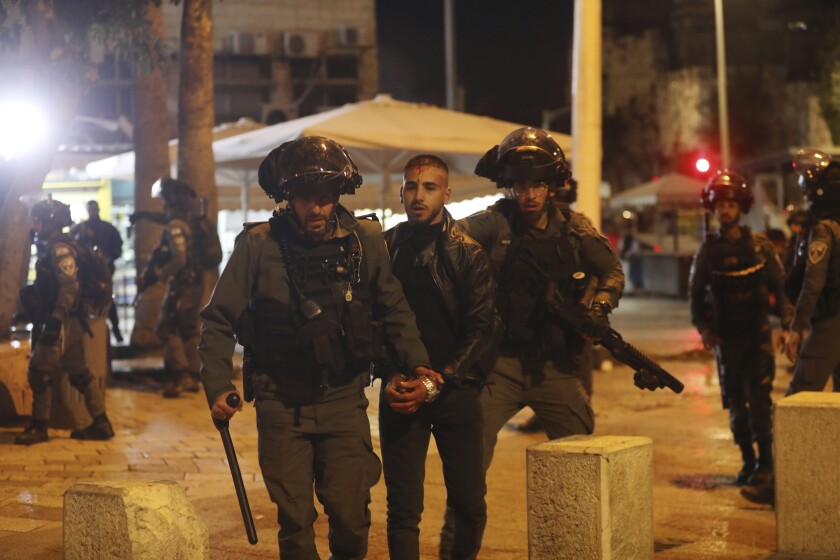 Un hombre herido es escoltado por la policía israelí después de que un hombre fuera baleado cerca de la Puerta de Damasco en la Ciudad Vieja de Jerusalén, el sábado 4 de diciembre de 2021. (AP Foto/Mahmoud Illean)
