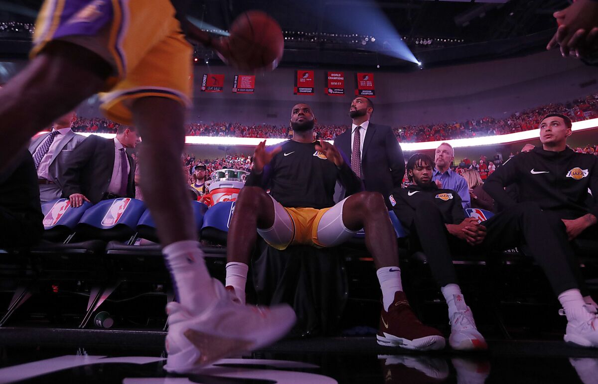 LeBron James sits on the bench before the start of the season operner in Portland on Oct. 18.
