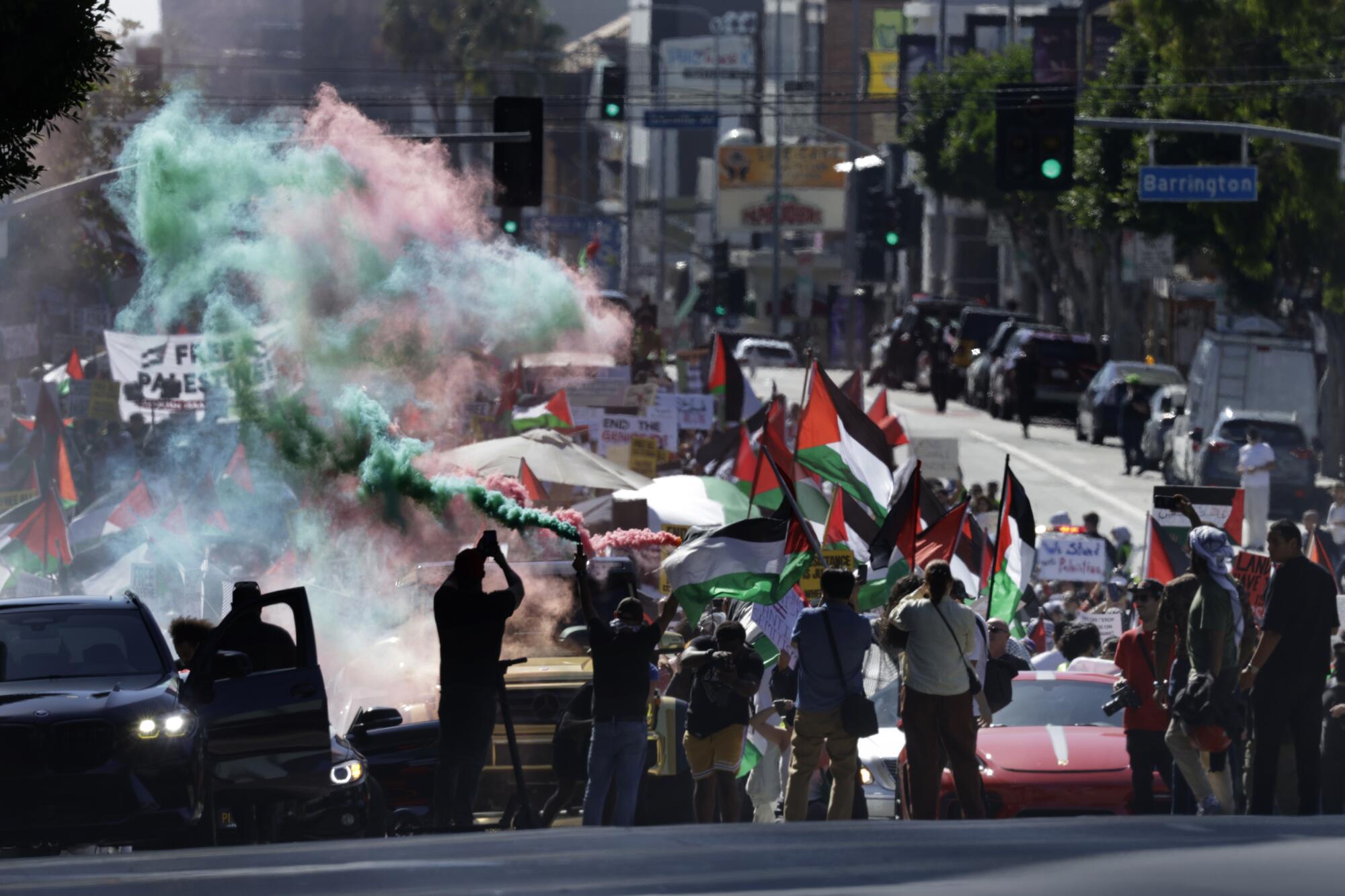 Demonstrators disperse green and red smoke in Westwood in support of Palestinians caught in the Israel-Hamas war.