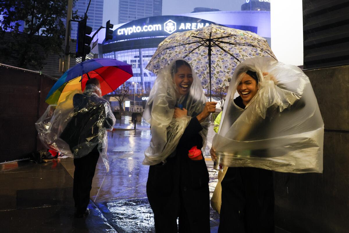 Two women huddle under umbrellas on a rainy February day in downtown Los Angeles. 