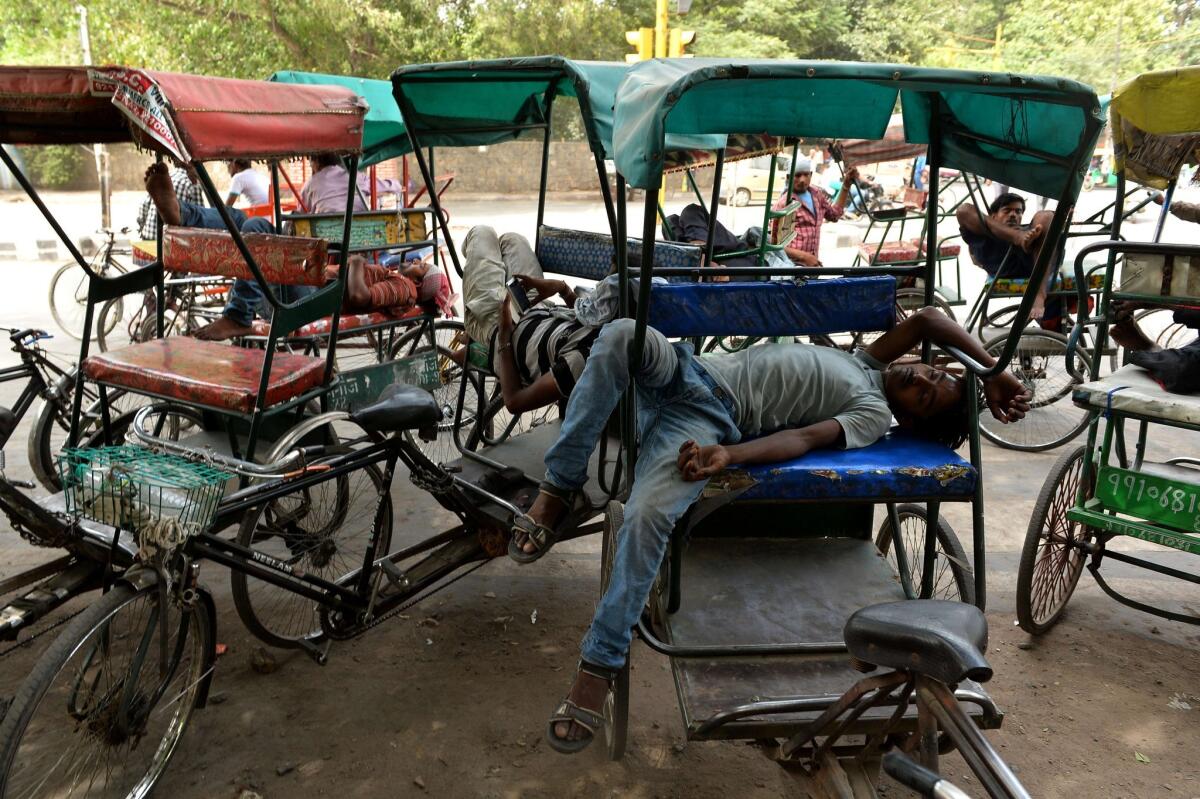 Indian cycle rickshaw riders sleep during the heat of the day in New Delhi.
