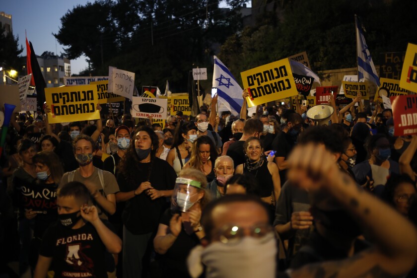 Demonstrators, defying orders to maintain social distancing requirements, chant slogans and blow horns outside the Prime Minister's residence in Jerusalem, Tuesday, July 14, 2020. Thousands of Israelis demonstrated outside the official residence of Benjamin Netanyahu, calling on the embattled Israeli leader to resign as he faces a trial on corruption charges and grapples with a deepening coronavirus crisis. (AP Photo/Ariel Schalit)