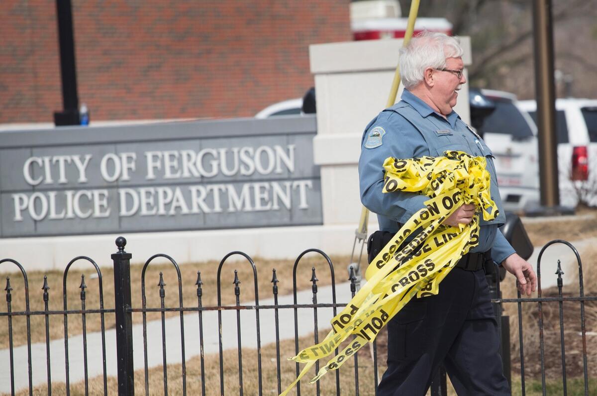An officer in Ferguson, Mo., removes crime scene tape from outside the police station following an investigation of the area after two officers were shot during a protest Wednesday night.