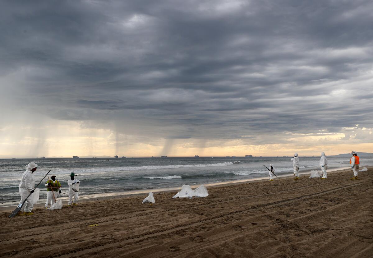 Cleanup workers in protective suits on Huntington State Beach