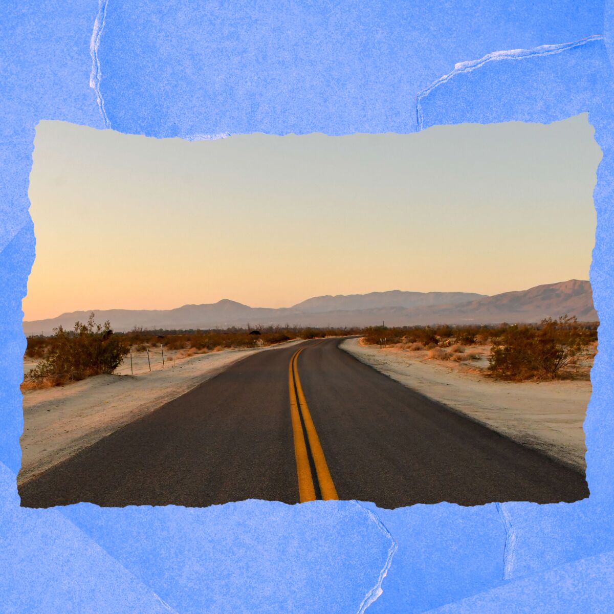 A paved road runs through the desert and toward hills.