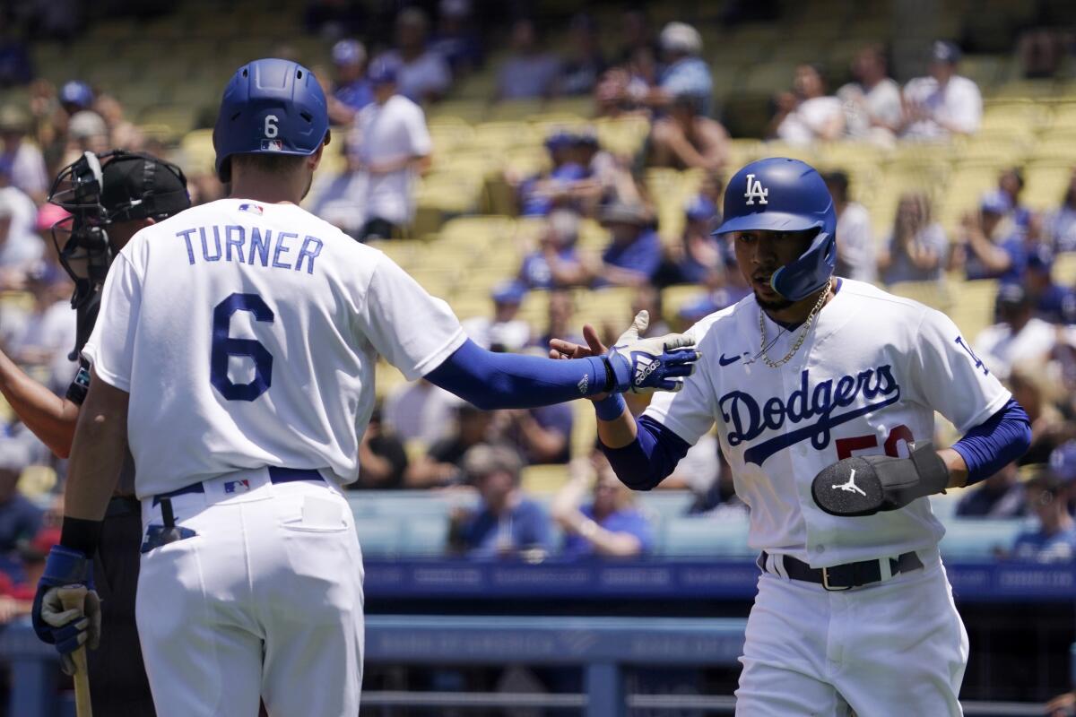 Dodgers' Mookie Betts is congratulated by Trea Turner after scoring on a single by Freddie Freeman.