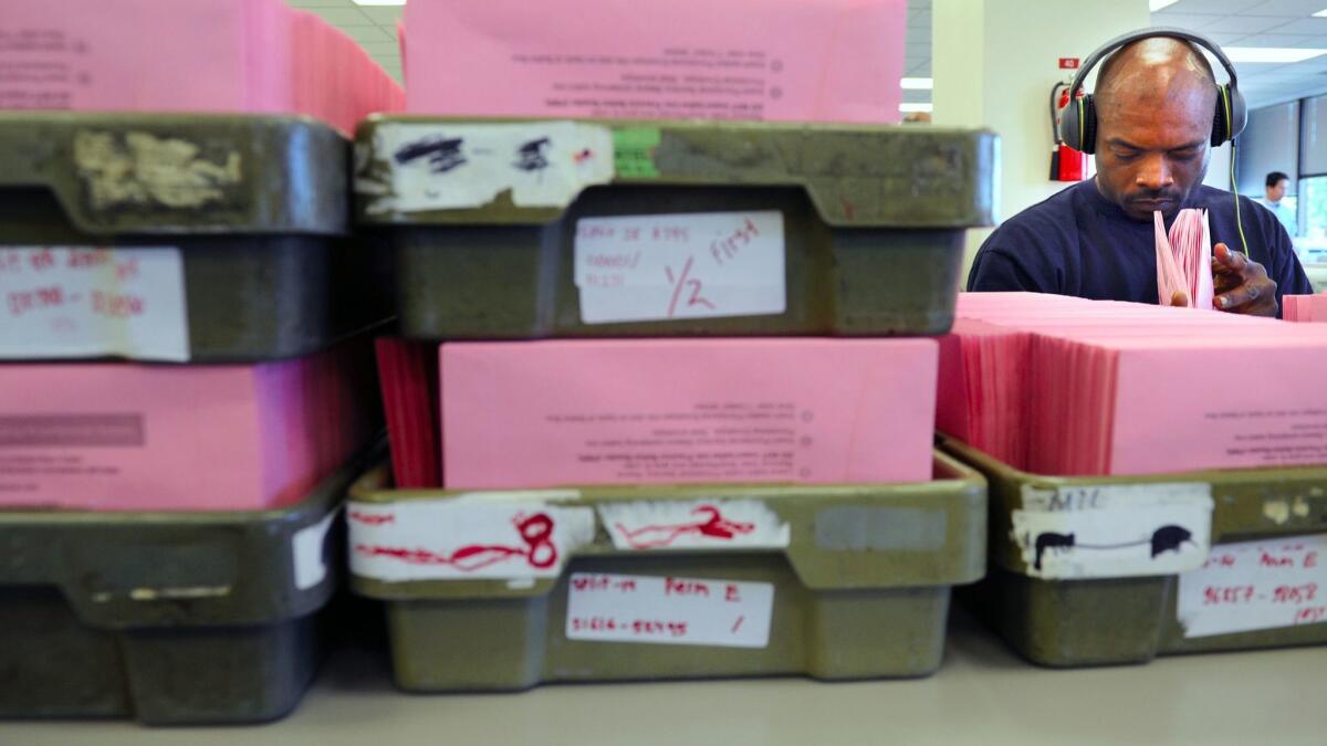 A worker counts absentee ballots at the L.A. County registrar-recorder's office in Norwalk. Since 1970, state law has said ballot measures take effect the day after an election, even when ballots remain uncounted.