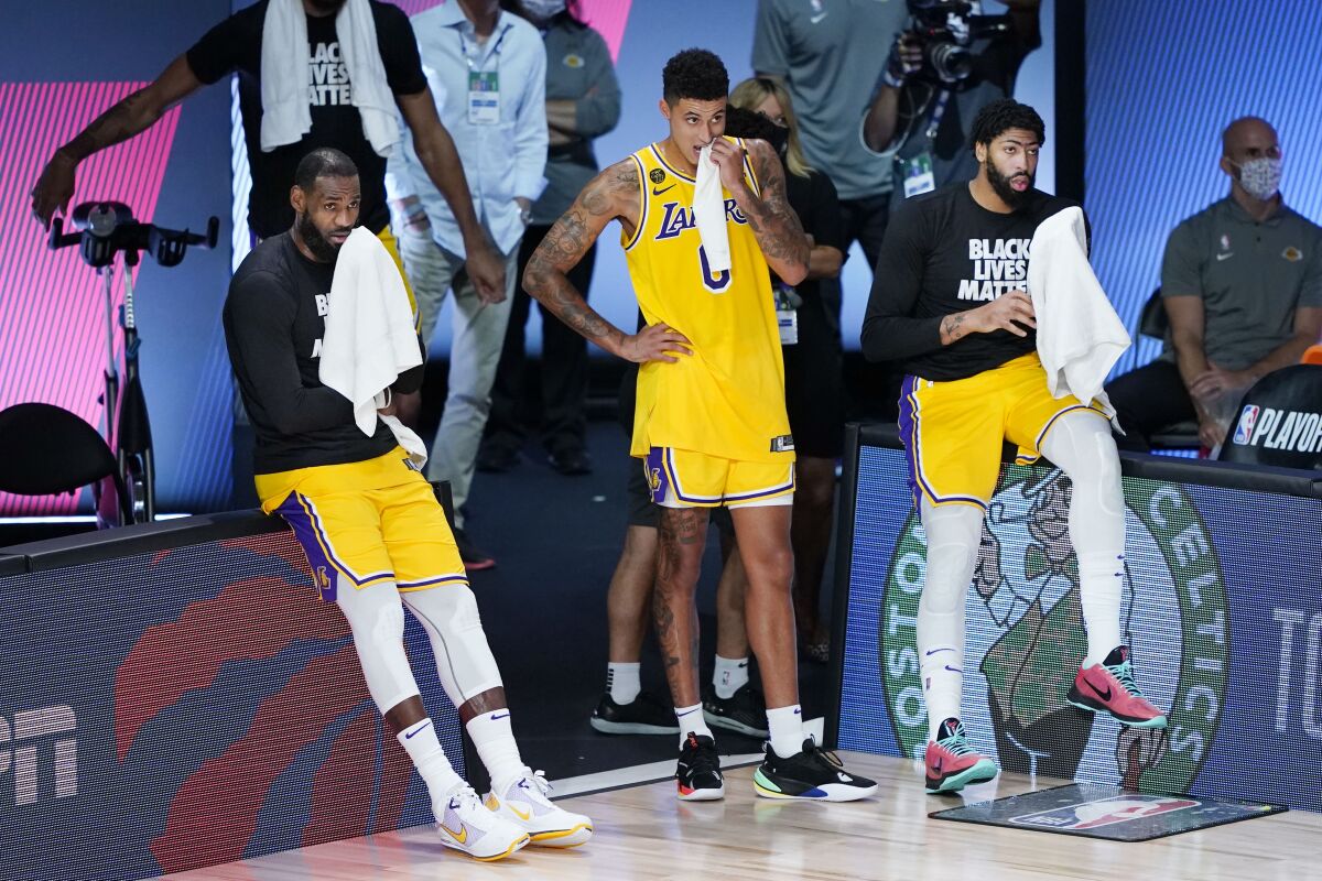 Los Angeles Lakers' LeBron James, left, Kyle Kuzma (0) and Anthony Davis, right, watch the final seconds of the fourth quarter of an NBA basketball first round playoff game against the Portland Trail Blazers Saturday, Aug. 29, 2020, in Lake Buena Vista, Fla. The Lakers won 131-122 to win the series 4-1. (AP Photo/Ashley Landis)