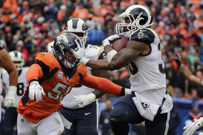 Rams running back Todd Gurley (30) keeps his hand on Denver Broncos linebacker Todd Davis (51) as he scores on a 4th and 1 play from the 10 yard line in the second quarter at Broncos Stadium at Mile High on Sunday.