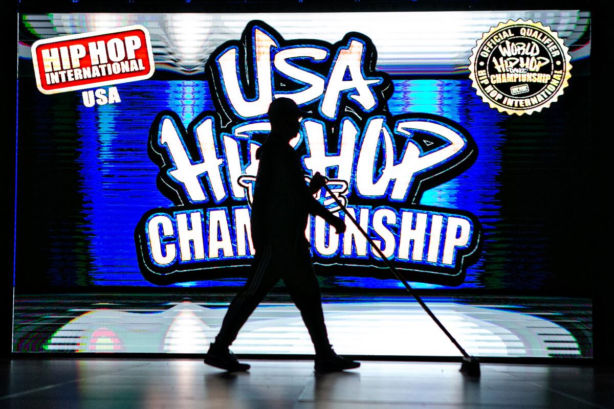 A staff member silhouetted against the logo of the 2021 USA Hip Hop Dance Championship