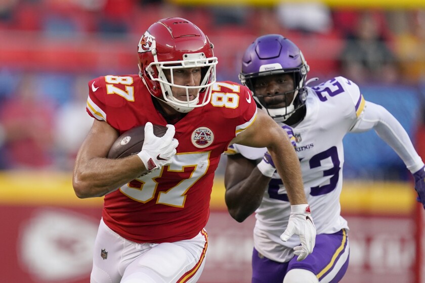 Kansas City Chiefs tight end Travis Kelce (87) runs with the ball as Minnesota Vikings safety Xavier Woods (23) defends during the first half of an NFL football game Friday, Aug. 27, 2021, in Kansas City, Mo. (AP Photo/Charlie Riedel)