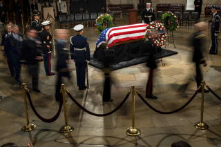 Military members in uniform stand by former President Carter's casket