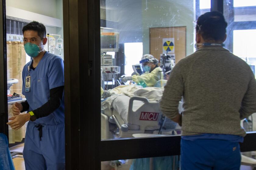 LOMA LINDA, CA - DECEMBER 15, 2020: Pulmonologist Dr. Laren Tan leaves a COVID-19 patient's room after checking on the patents oxygen levels in the ICU at Loma Linda University Medical Center on December 15, 2020 in Loma Linda, California. The hospital is experiencing a huge surge in COVID-19 patients. Dr. Michael Matus, chief of hospitalist said they are currently admitting more than 15 patients a day. The hospital has added 5 additional Covid units in addition to ICU. Many of the ICU patients have underlying health issues. Once those patients get Covid, "It's a marathon that they can't run, said Dr. Tan.(Gina Ferazzi / Los Angeles Times)