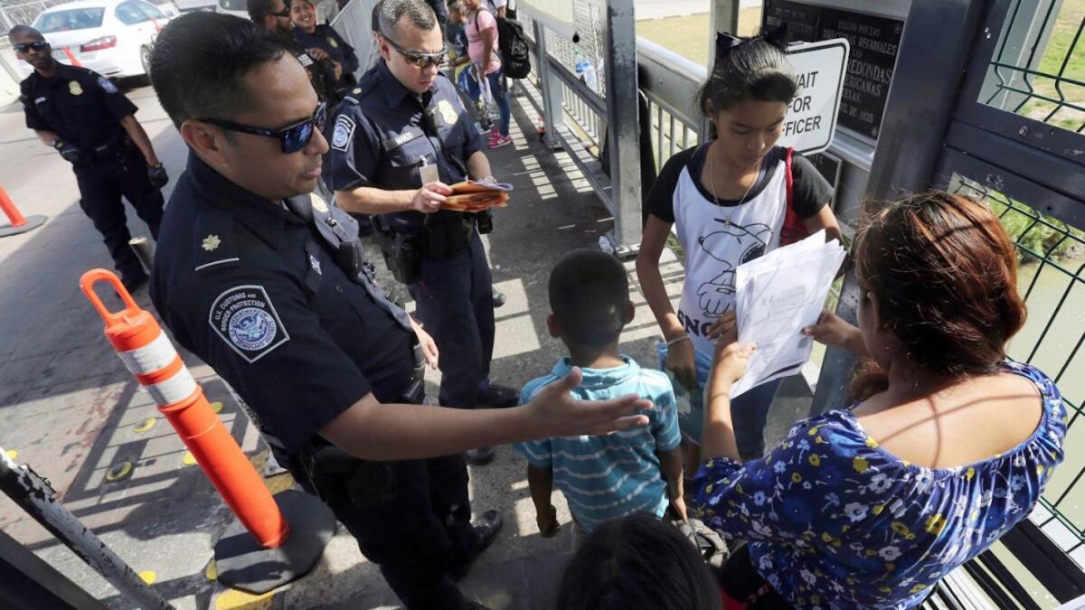 Un agente de la Oficina de Aduanas y Protección Fronteriza verifica los documentos de migrantes antes de que sean llevados a solicitar asilo en Estados Unidos, en el Puente Internacional 1 en Nuevo Laredo, México.