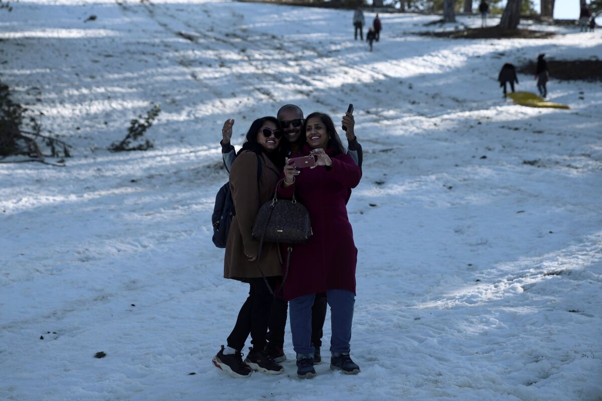 People take selfies as they enjoy the snow on Troodos mountains in the eastern Mediterranean island of Cyprus, on Saturday, Dec. 11, 2021. (AP Photo/Petros Karadjias)