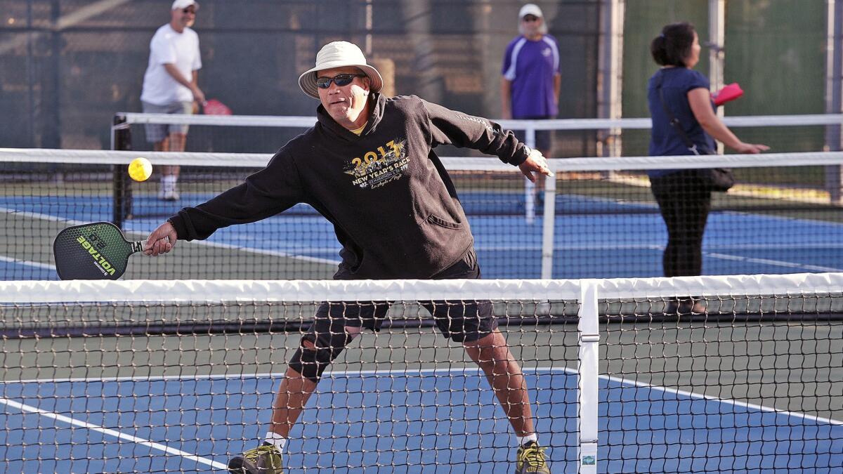 Roland Sunga of Burbank reaches to hit the ball back into play on opening day of full-time pickleball courts at Larry Maxam Memorial Park on April 9.