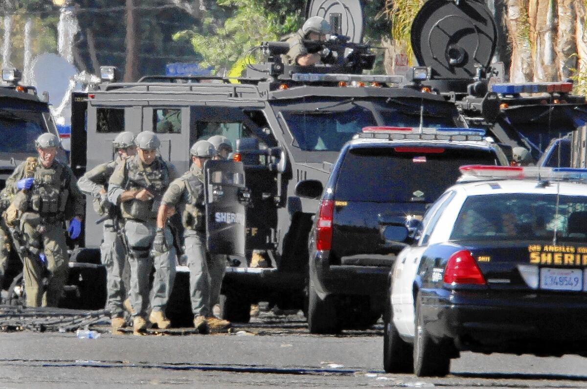 A Los Angeles County Sheriff's Department SWAT team is deployed during a standoff at a Lynwood apartment after a man shot a sheriff's detective in the shoulder. The man was later shot and killed by deputies when he emerged from the apartment with a gun.