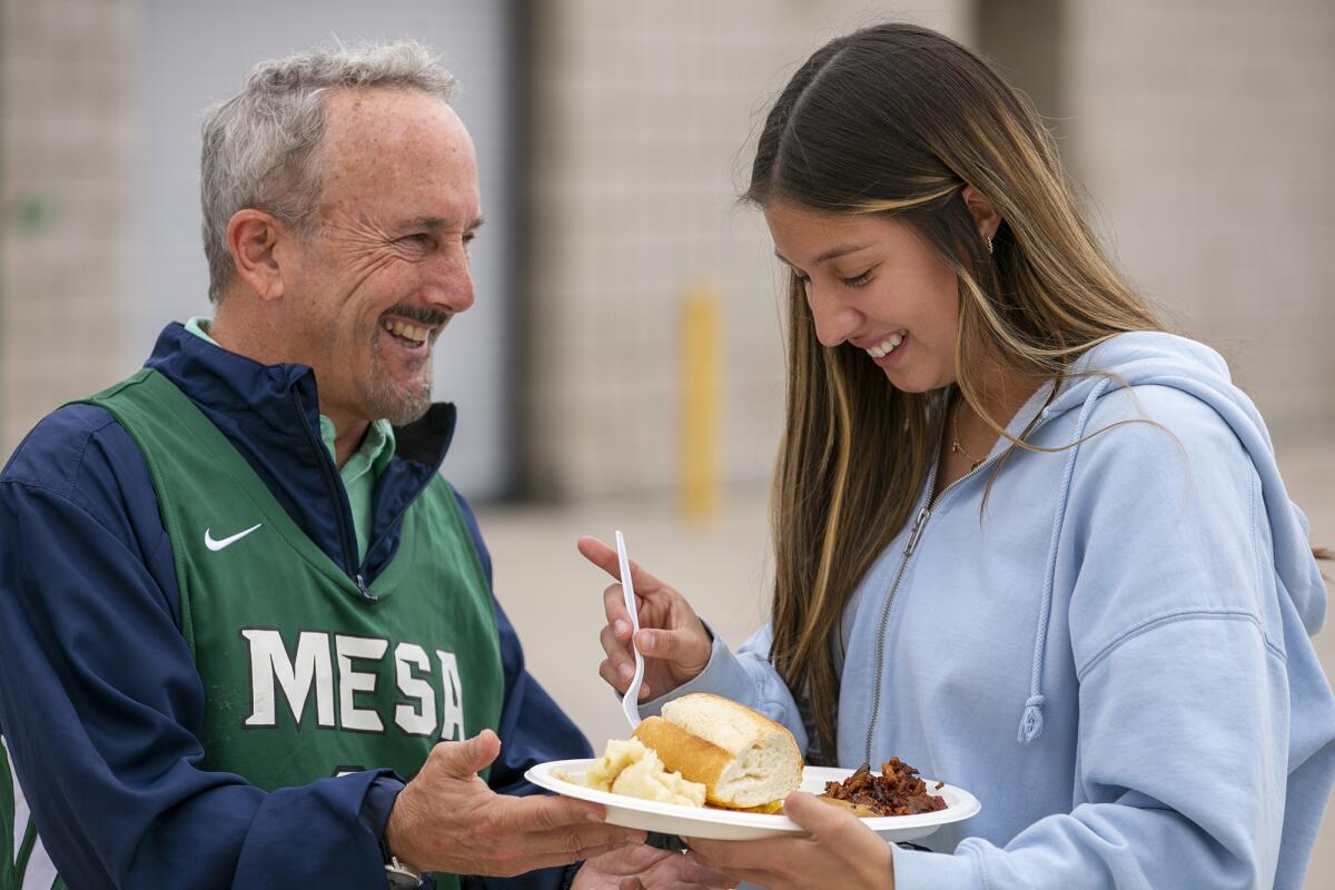 John Ursini, the owner of Newport Rib Co., holds a plate of food for Natasha Ruiz, a Costa Mesa girls' volleyball player.