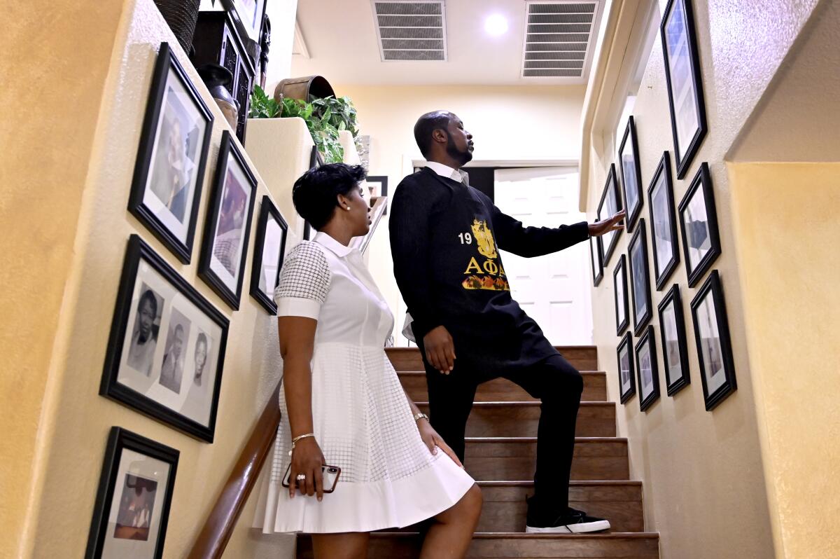 Allen and Wendy Shelton look at family photos hanging in a stairwell of their home.
