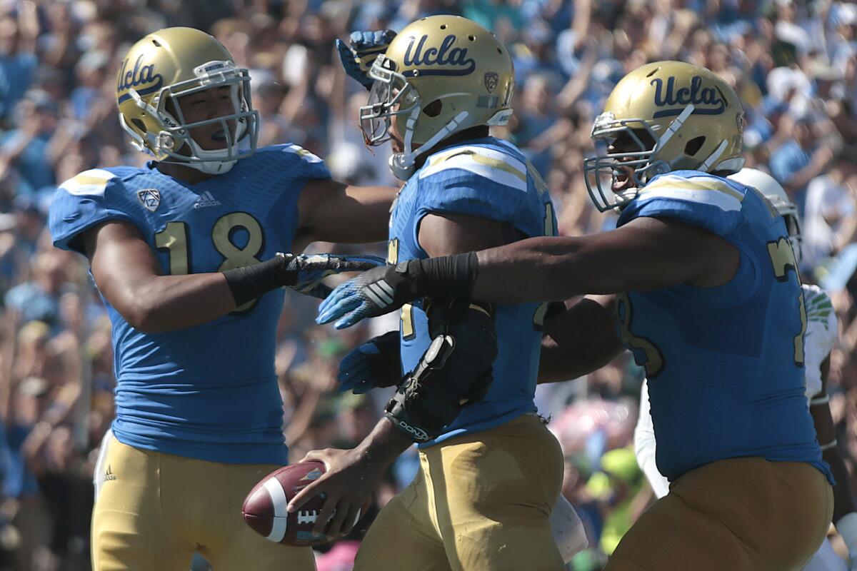 UCLA receiver Thomas Duarte, left, and offensive lineman Malcolm Bunche, right, congratulate quarterback Brett Hundley after he scored on a 16-yard run against Oregon on Oct. 11.