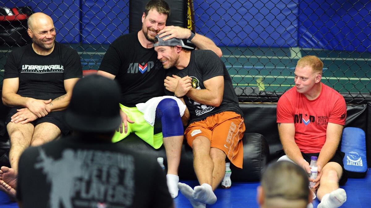 Former NFL quartback Ryan Leaf gives former college football player and Green Beret Nate Boyer a hug during a meeting that included former MMA fighter Randy Couture, left, and former Marine Tim Astorino, right, at the Unbreakable Performance Center in Hollywood.