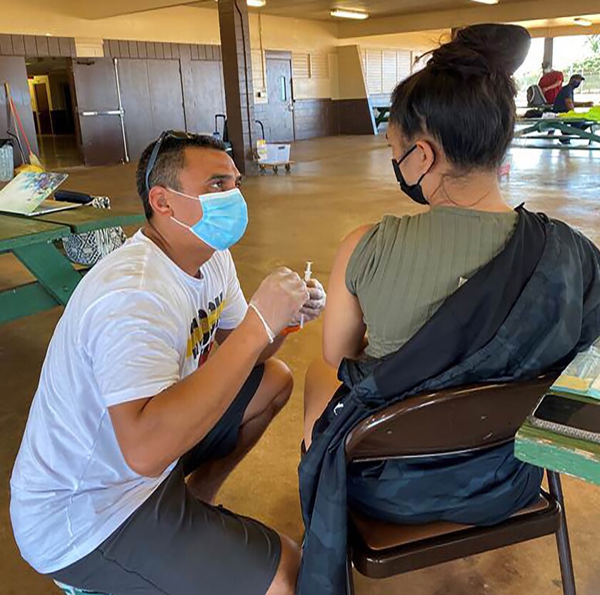 In this photo provided by Bryden Kaauwai, Dr. Kapono Chong-Hanssen administers COVID-19 vaccines, Saturday, July 10, 2020, in Kekaha, Hawaii. Chong-Hanssen supports a resolution introduced by a member of the Honolulu City Council urging Hawaii government agencies to go beyond minimum federal standards and get more specific when collecting racial data in one of the most racially diverse state in the nation. Chong-Hanssen said the pandemic underscores the need for data that doesn't lump together Pacific Islanders. (Bryden Kaauwai via AP)