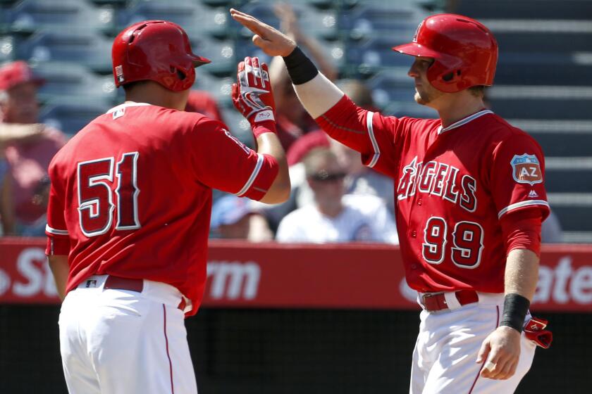 Angels teammates Ji-Man Choi (51) and Taylor Ward (99) celebrate after scoring against the Cubs on a single by David Fletcher in the eighth inning Sunday.