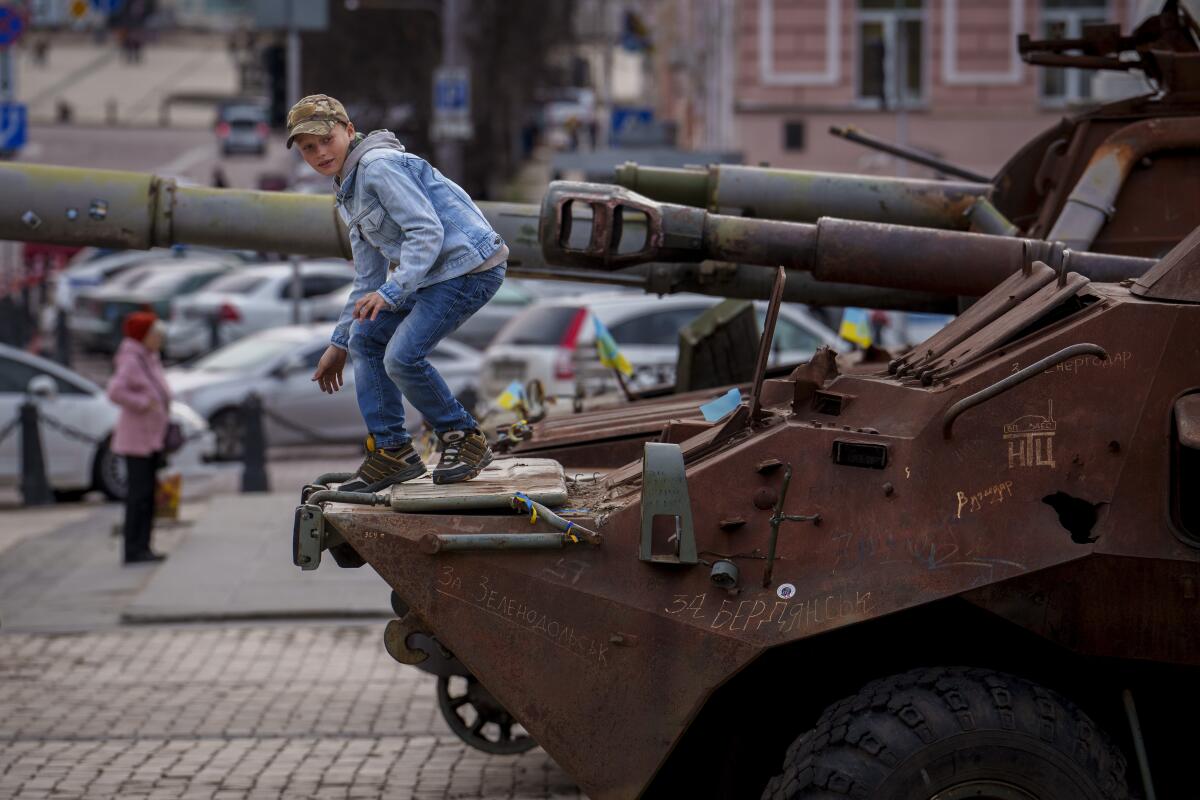 A child climbs on a rusty armored personnel carrier