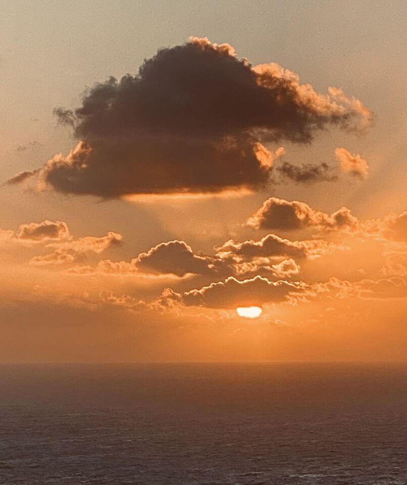 The setting sun peeks through clouds off the La Jolla coast.