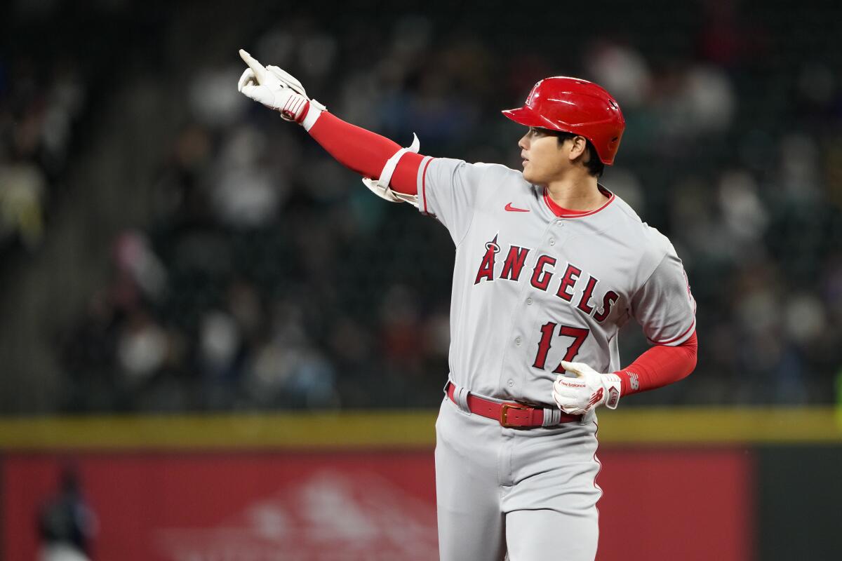Angels designated hitter Shohei Ohtani points to the outfield as he runs the bases after hitting a two-run home run.
