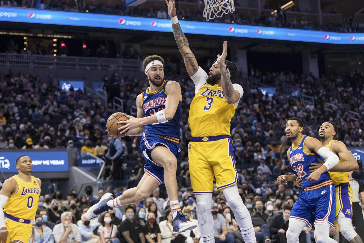 Lakers forward Anthony Davis forces Warriors guard Klay Thompson to pass the ball.