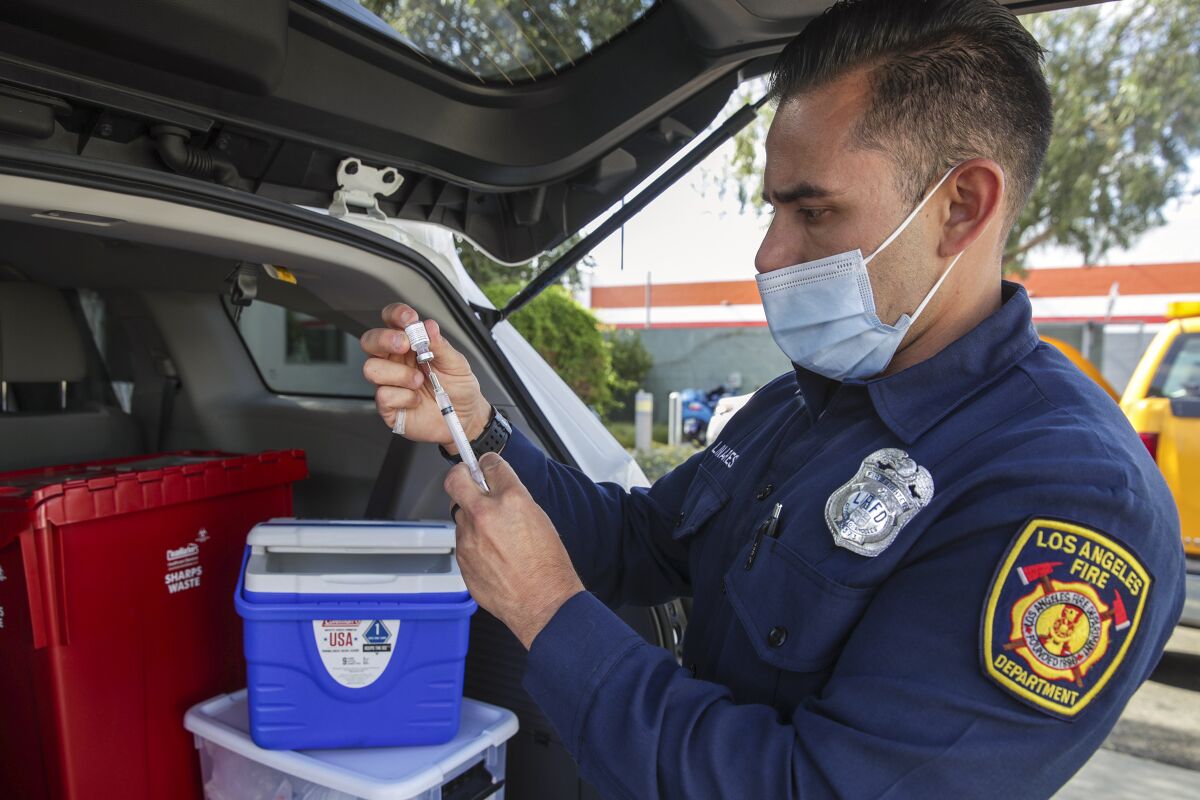A Los Angeles firefighter-paramedic prepares a COVID-19 vaccine.